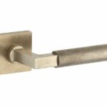 Deurkruk op geveerd rozet verdekt Bauhaus messing antiek